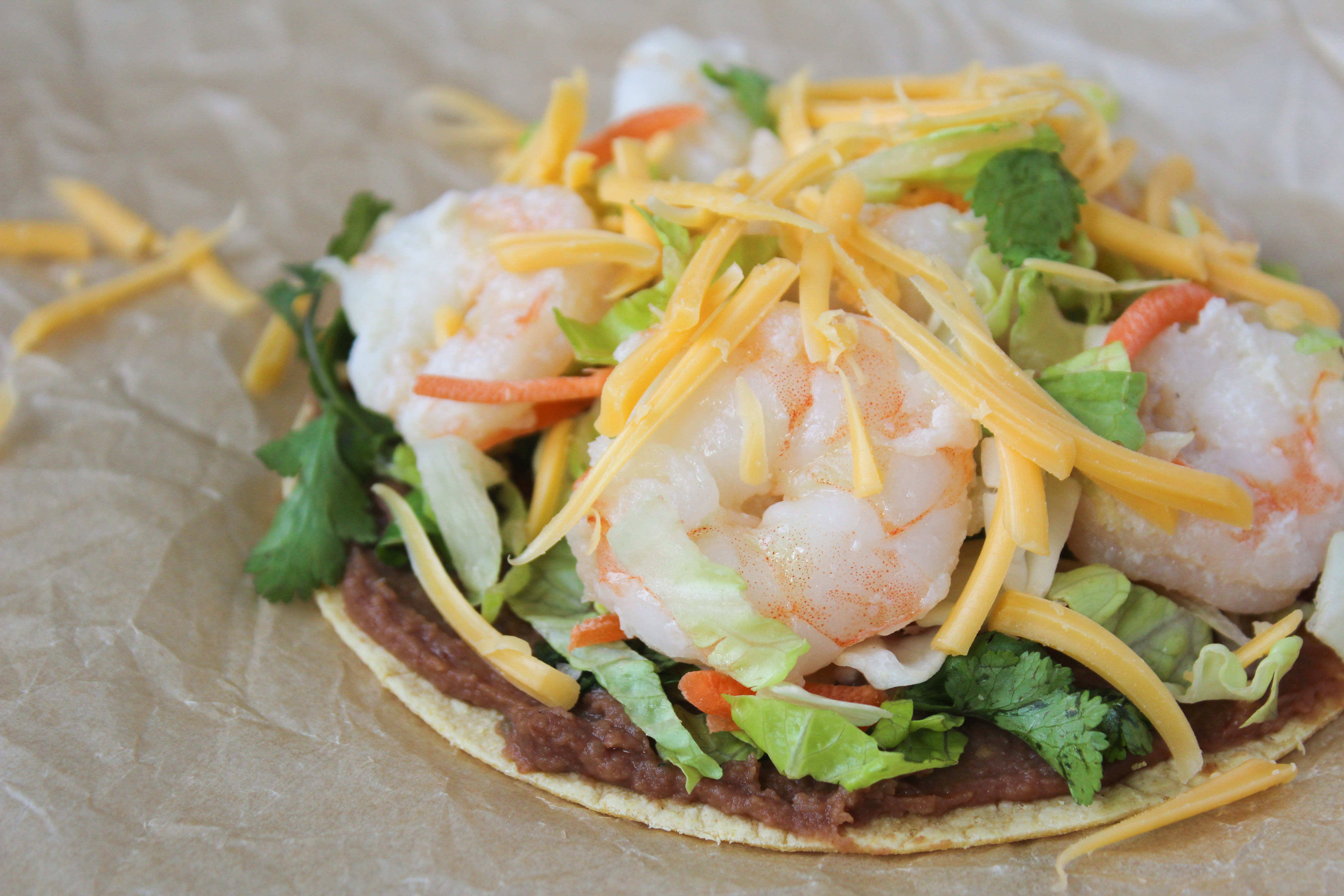 Shrimp tostada with refried beans and cheddar cheese sprinkled on top. 