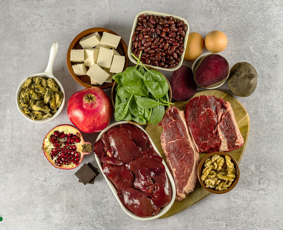 An array of iron-rich foods, showcasing both animal sources like red meat and poultry for heme iron, alongside plant-based options such as beans, spinach, and fortified cereals for non-heme iron, with citrus fruits